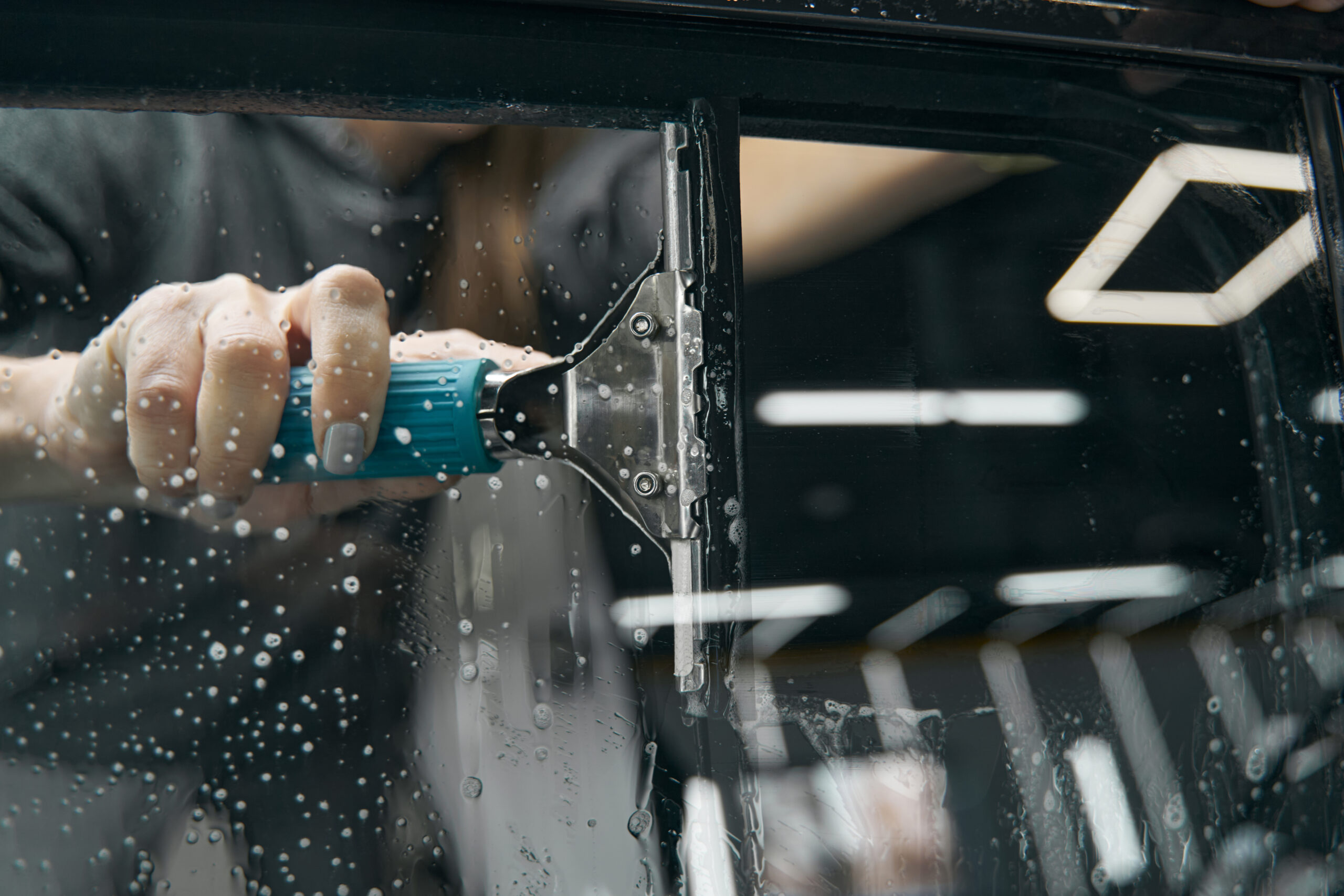 Professional hand washing a car window with foam during mobile exterior detailing