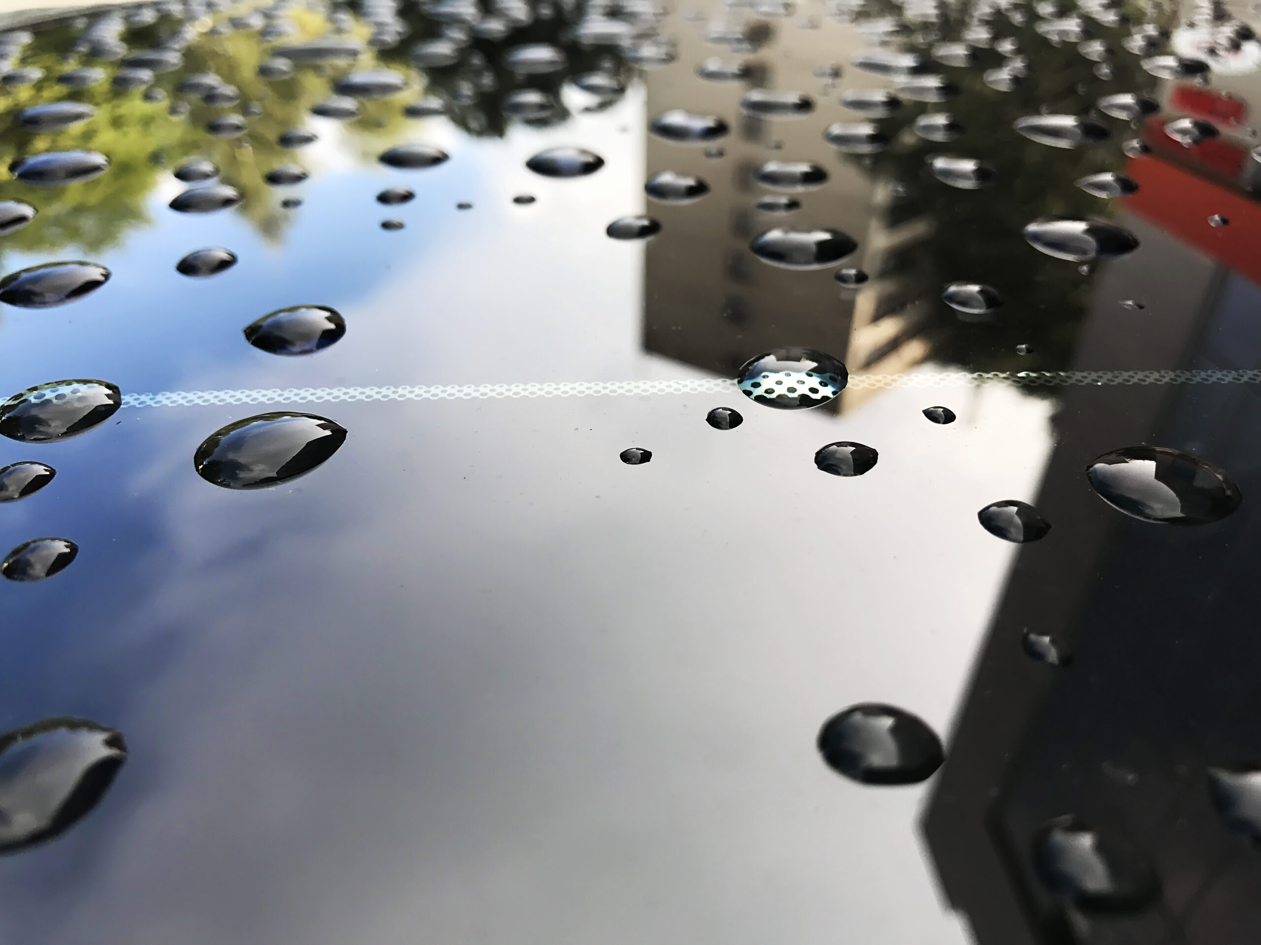 Water droplets beading on a hydrophobic sealed paint surface