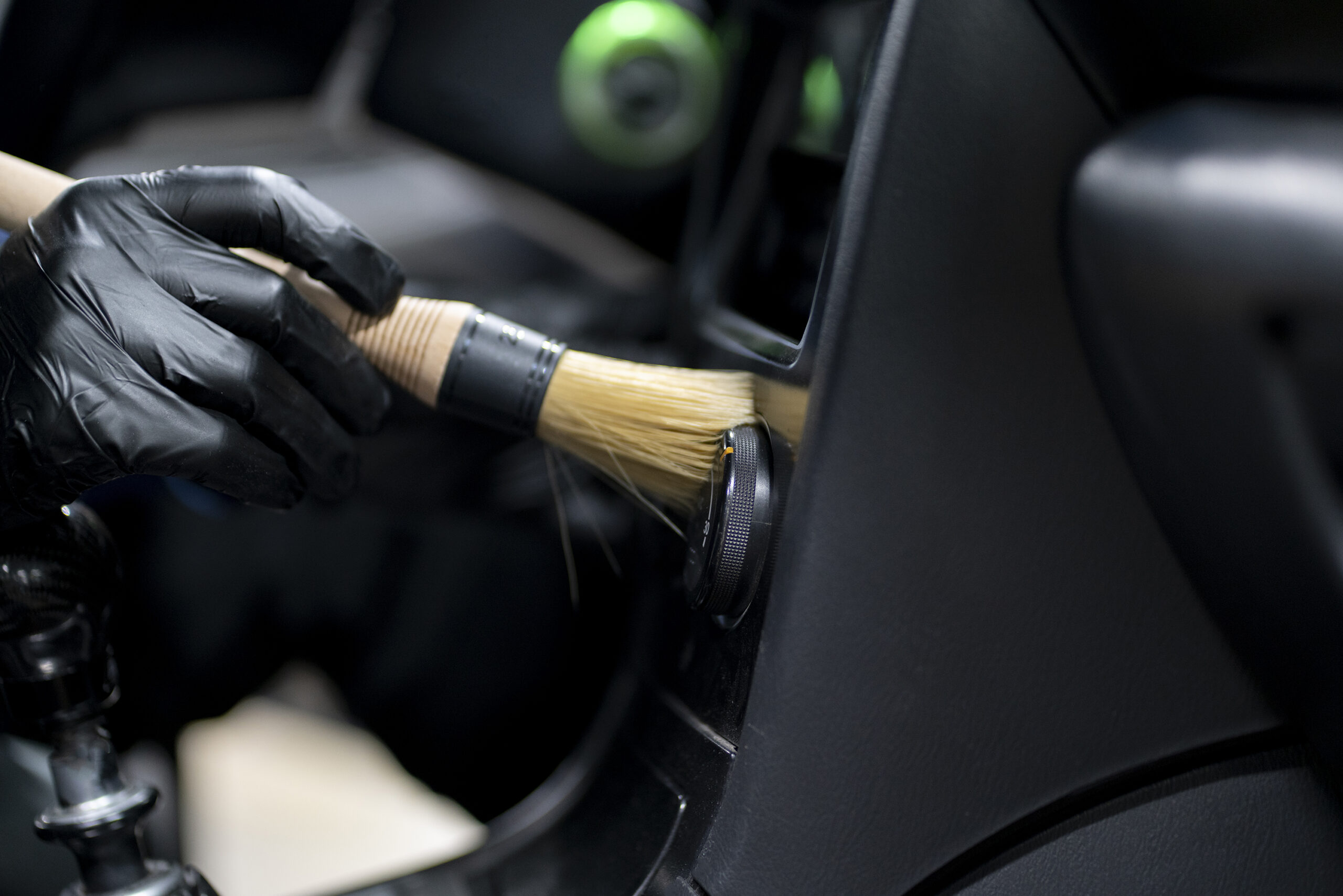 Professional detailer cleaning a car interior with a detail brush during mobile interior detailing
