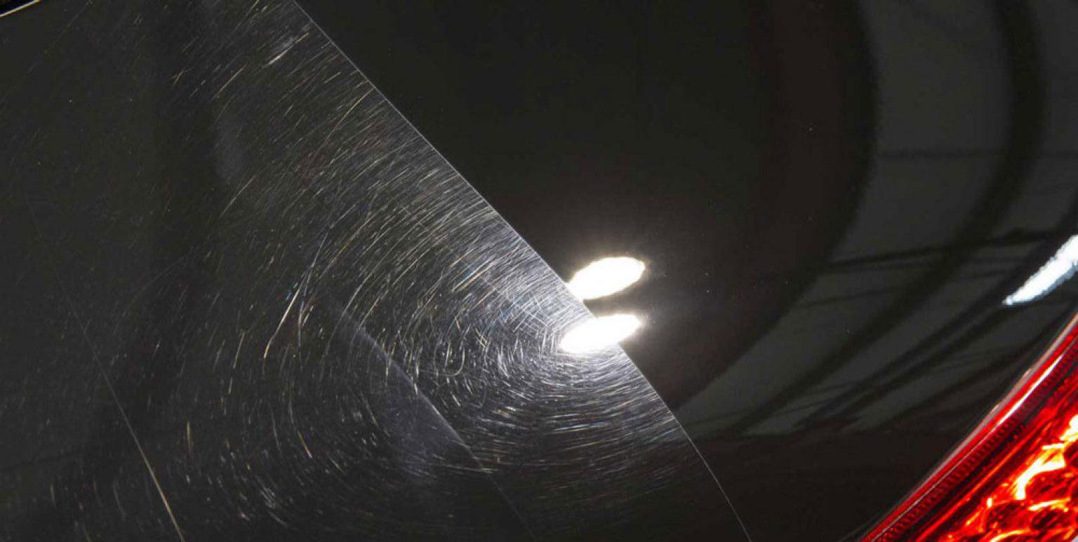 Swirl marks and fine scratches visible on black car paint before correction