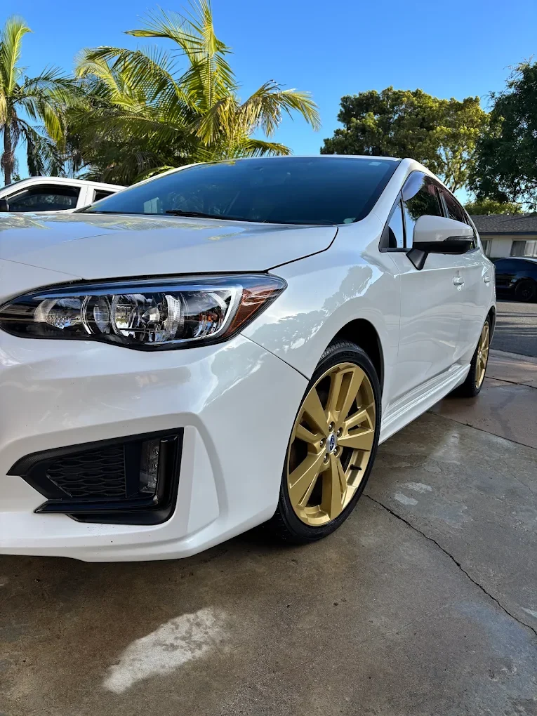 White Subaru WRX with gold wheels freshly detailed
